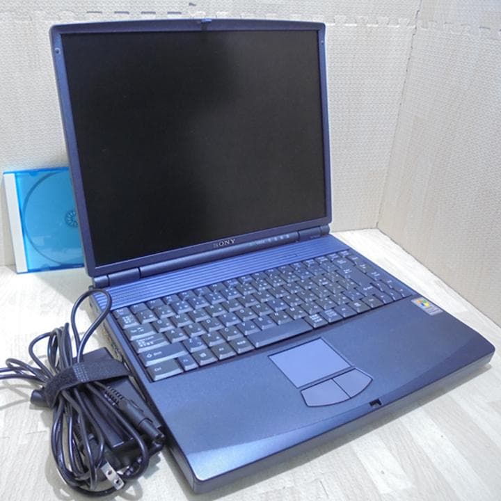 Sony VAIO laptop PCG-FX55J/B shown open with the screen off, keyboard visible and the power adapter coiled beside it.