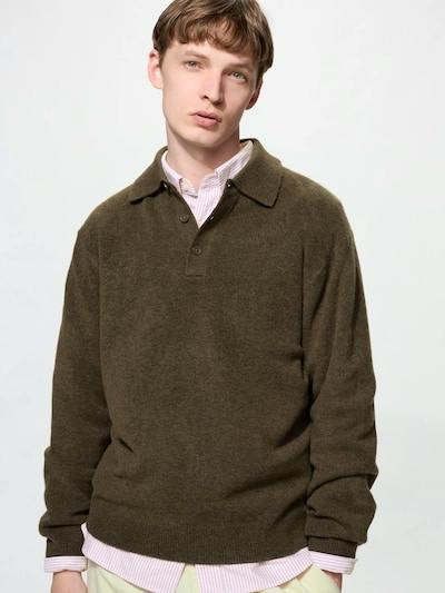 Male model wearing an olive-brown polo sweater over a pink button-up shirt against a plain white background.