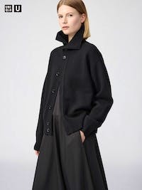 Model wearing a black relaxed button-up cardigan with a high collar and long sleeves.