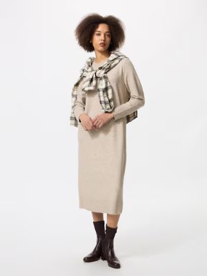 Model wearing a beige acrylic women's dress standing against a white background.
