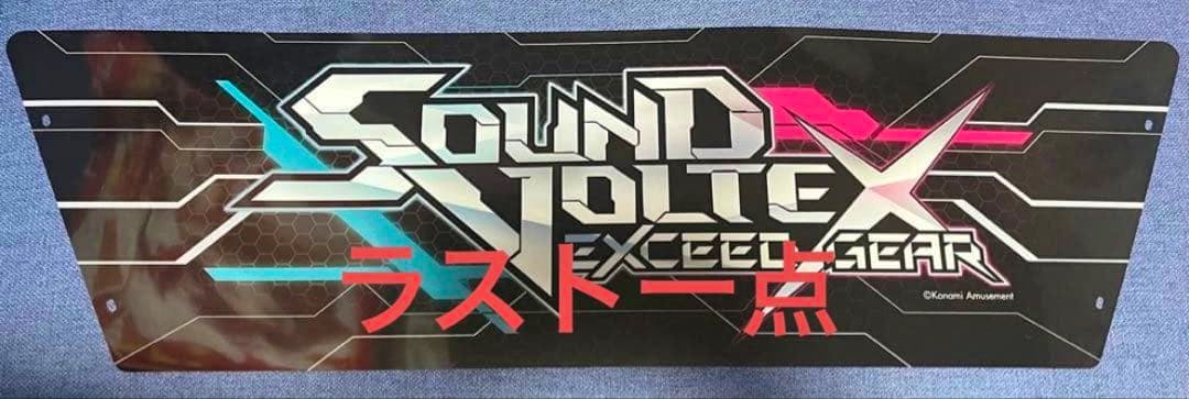 Rectangular acrylic panel showing the 'SOUND VOLTEX EXCEED GEAR' logo with red Japanese text on a black patterned background.