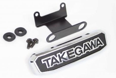 A TAKEGAWA steering stem emblem kit including the chrome emblem, mounting bracket, two screws, and washers.