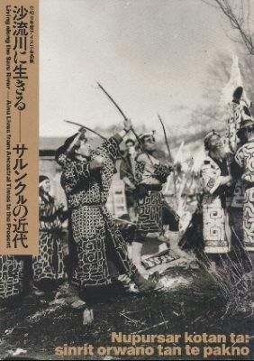 Cover of the exhibition catalog showing a black-and-white photograph of people in traditional dress with vertical Japanese title text on the left.