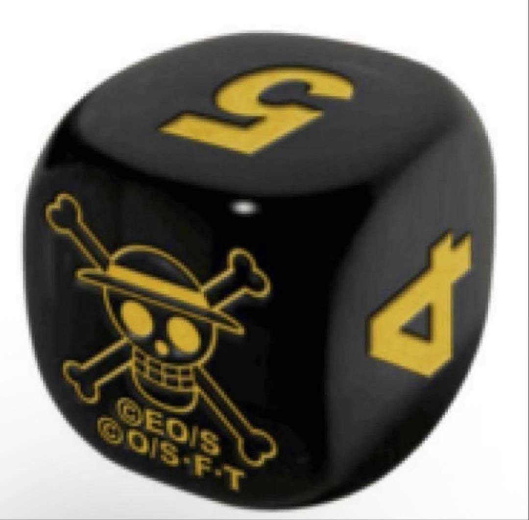 Close-up of a black six-sided plastic die showing gold numbers and a skull-and-crossbones logo.