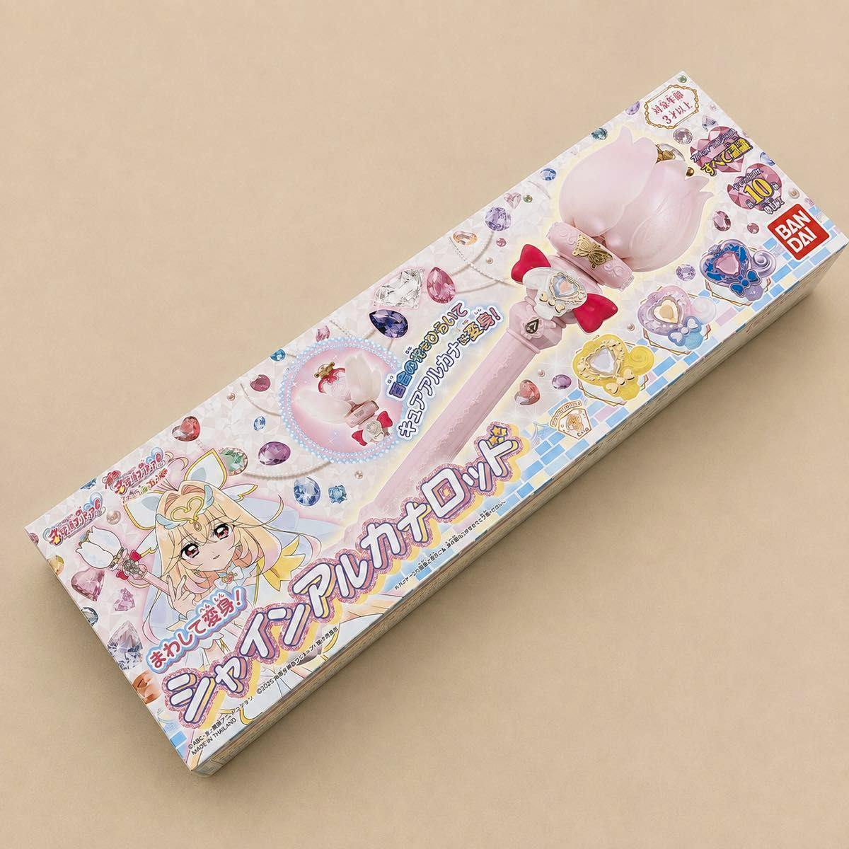 Photo of the boxed シャインアルカナロッド toy wand showing the packaging artwork and product image on a beige background.