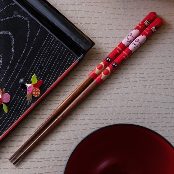A pair of wooden 21cm chopsticks with red decorated upper ends placed beside a lacquer tray and a red bowl.