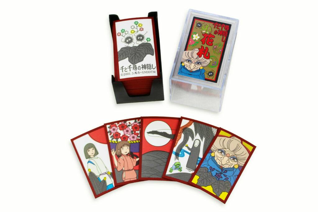 Photograph of Spirited Away–themed hanafuda cards fanned out with a clear plastic box and a black card stand.