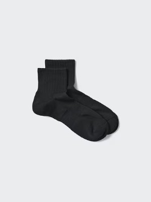 A pair of black sports half socks laid flat on a light background.