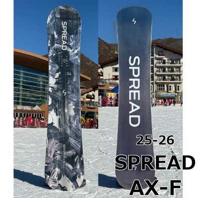 Front and back views of the 2025-2026 SPREAD snowboard standing upright on snow with buildings behind it.