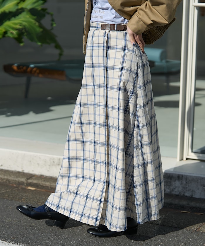 Side view of a spring checked wrap skirt in cream and blue worn by a model standing outdoors.