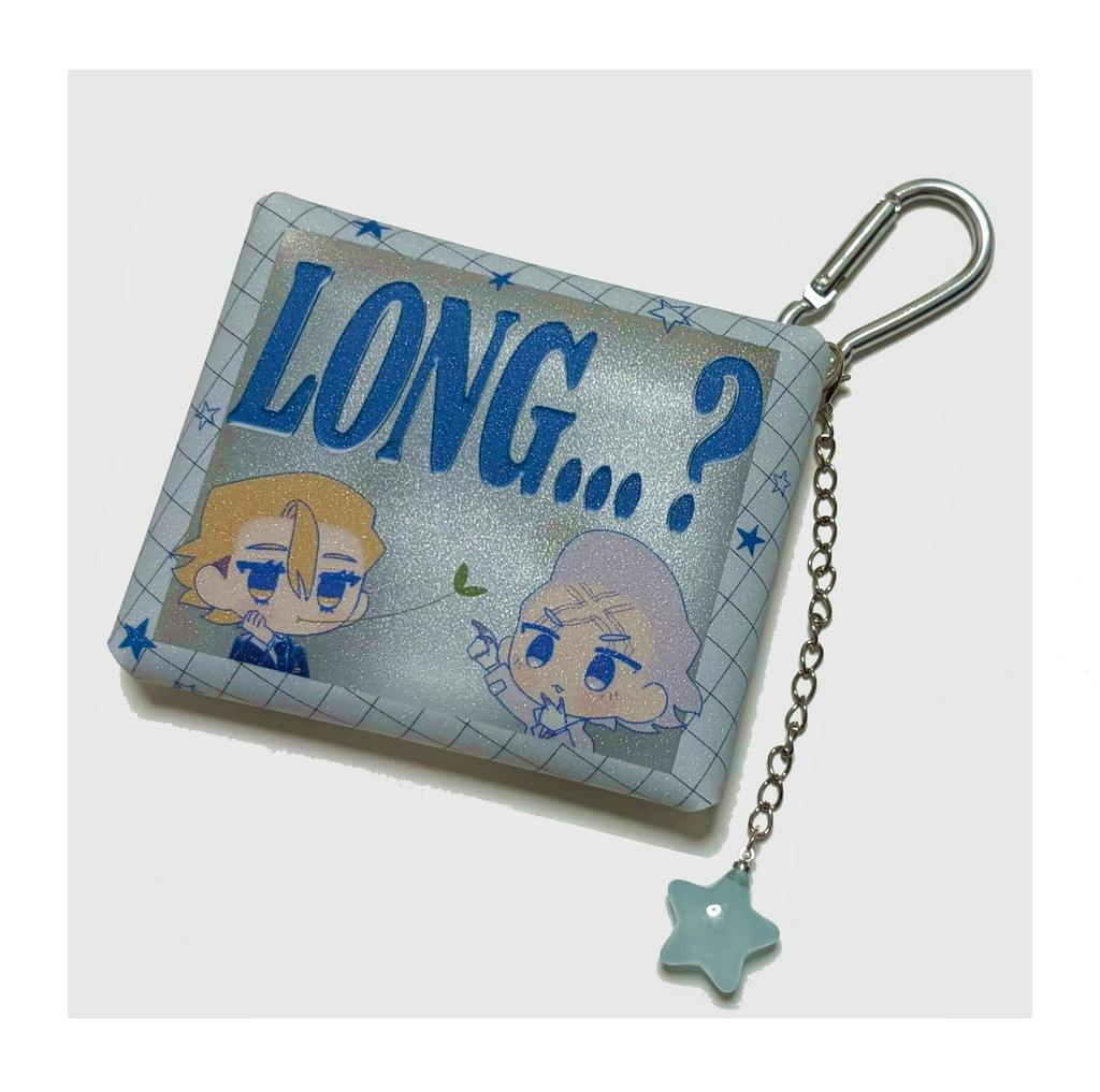 Square PVC case with printed characters and the text "LONG...?", shown with an attached chain, metal carabiner, and star charm.