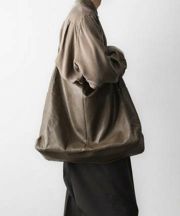 Olive goat leather shoulder bag worn over a model's shoulder, shown in side view.