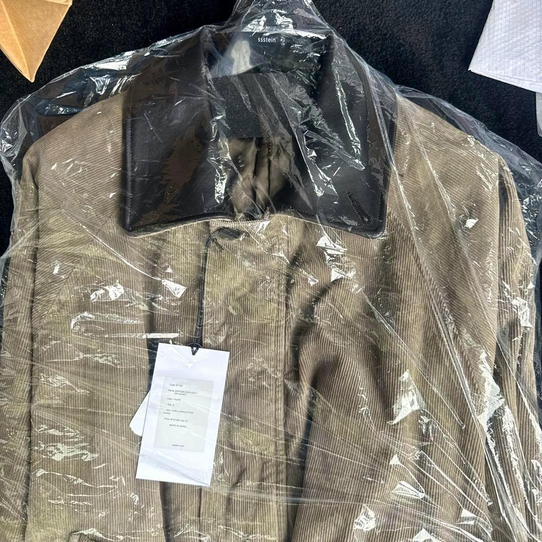 Mens corduroy zip jacket with a contrasting dark collar shown under a clear plastic cover with tags visible.