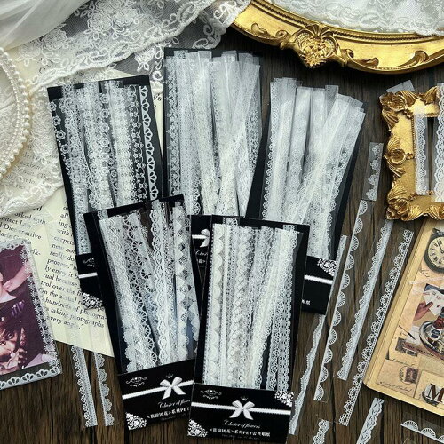 Photo of multiple packs of white lace decorative strips on black backing cards arranged on a wooden surface.
