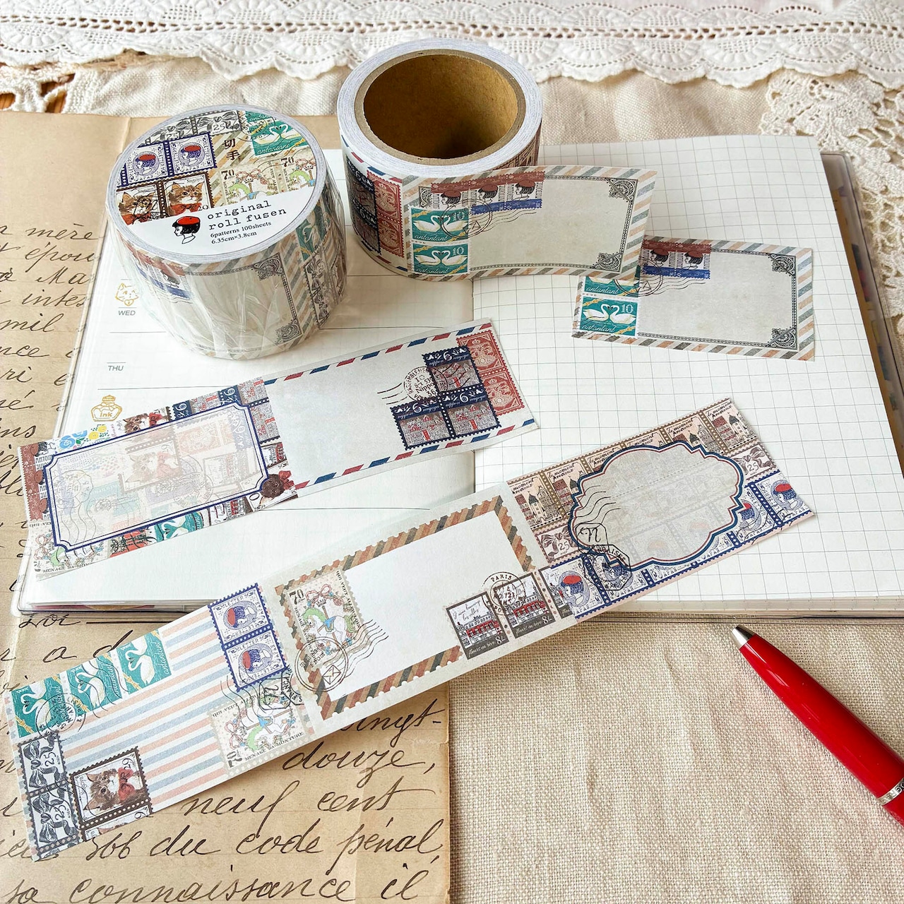 Rolls of stamp-pattern sticky notes with several unwrapped note labels displayed on a notebook.