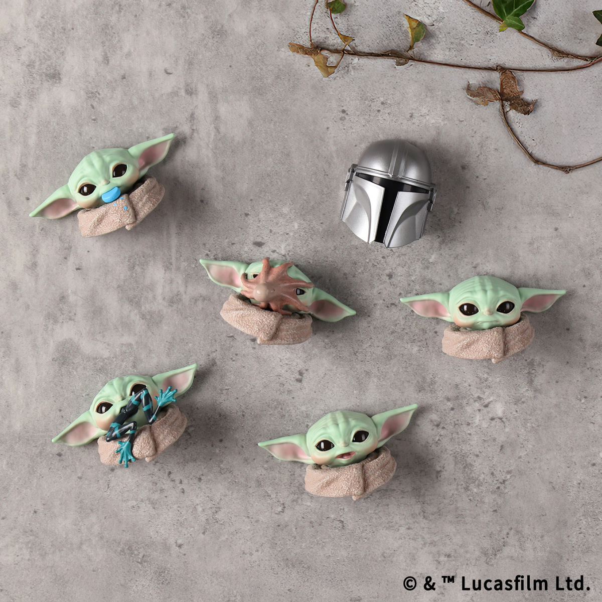 Several Star Wars The Mandalorian face fridge magnets, showing multiple Grogu (Baby Yoda) heads and a Mandalorian helmet arranged on a gray surface.