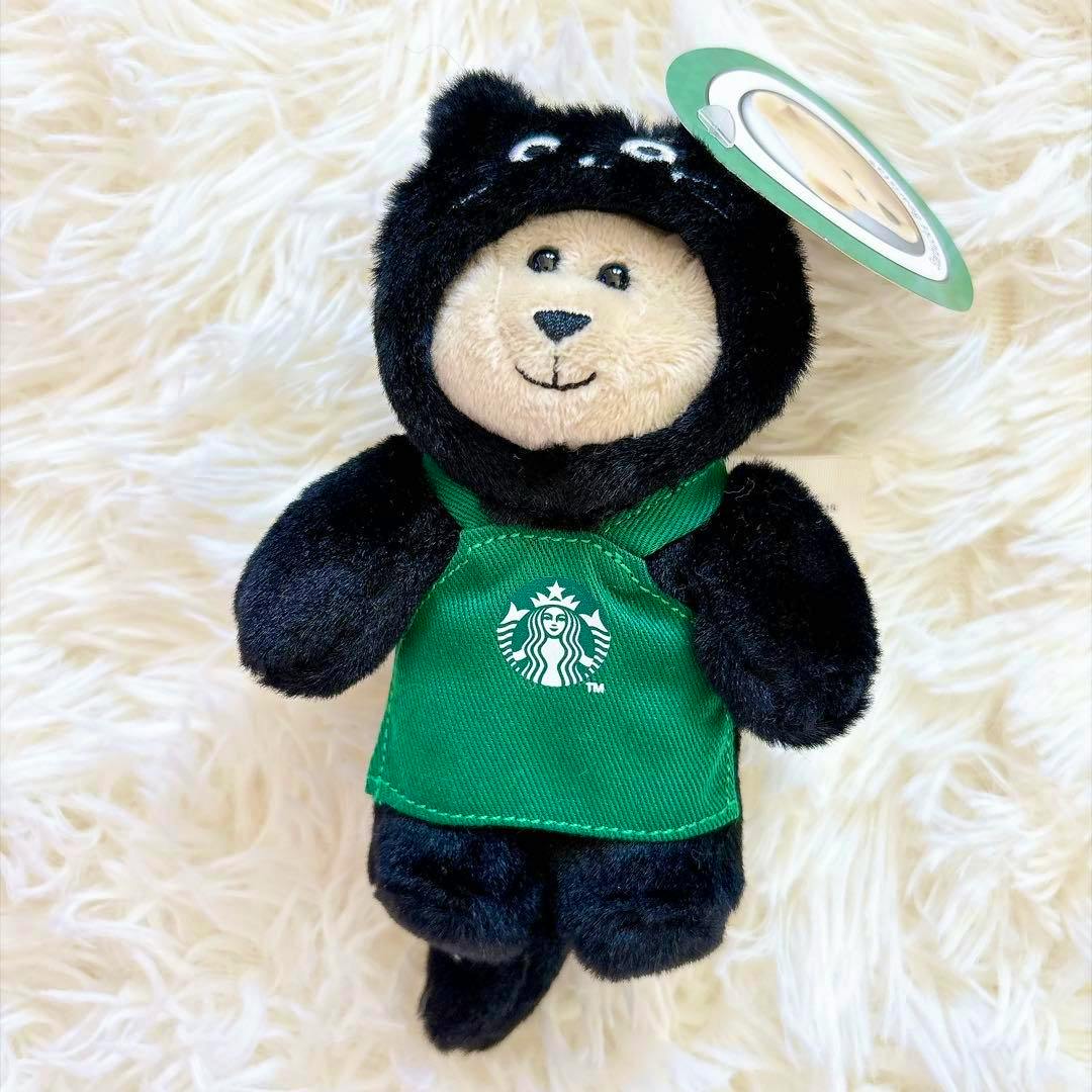 Front view of the Starbucks Bearista Mini plush in a black cat costume wearing a green Starbucks apron.