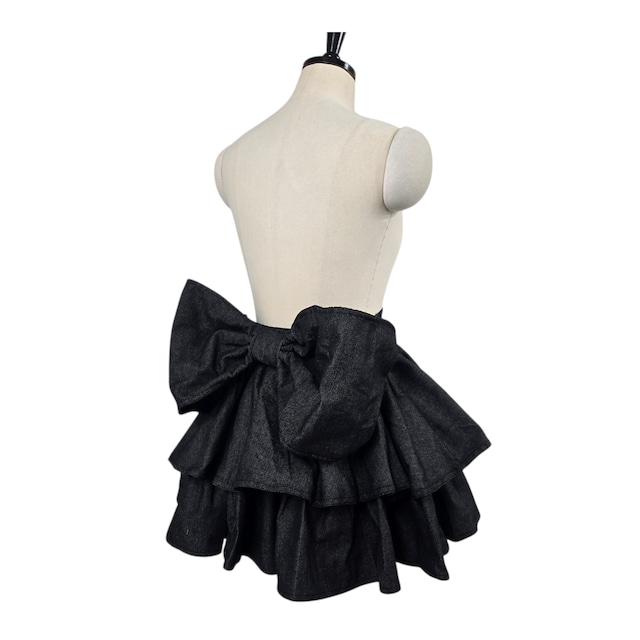 Dark denim frilled mini skirt with a large back bow shown on a dress form.