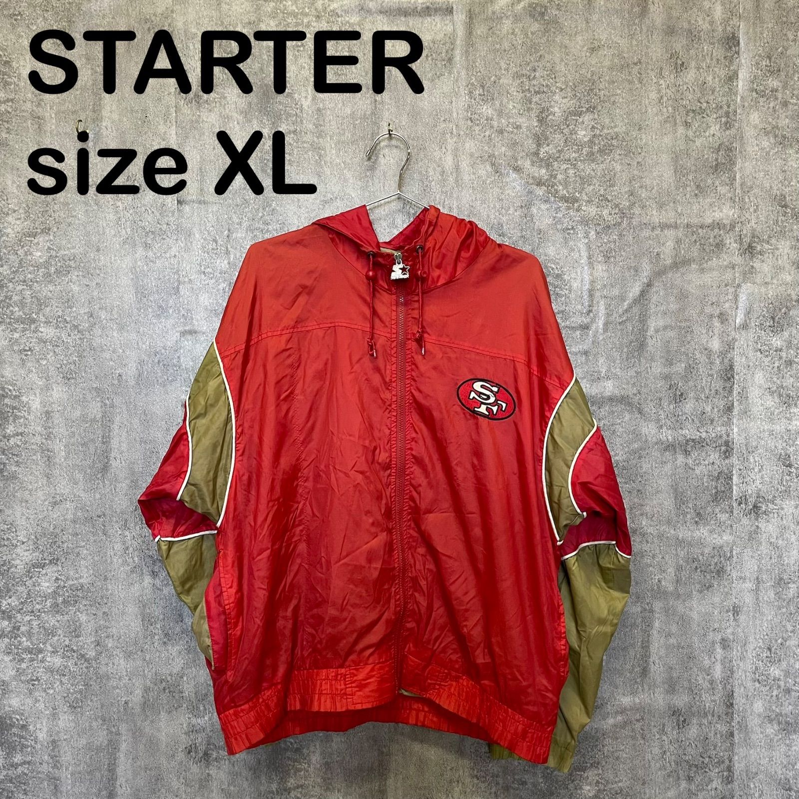 Red STARTER nylon San Francisco 49ers hooded men's jacket (size XL) hanging on a hanger against a gray background.