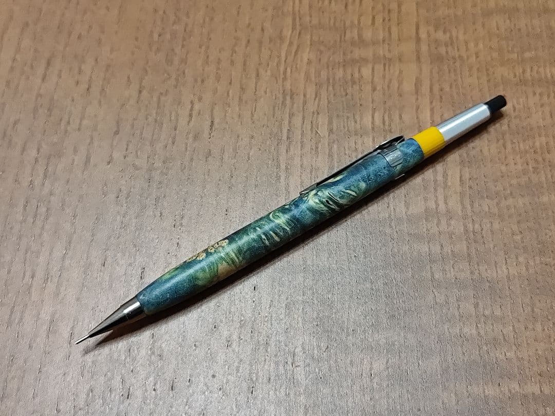 Mechanical pencil with a stabilized wood body lying on a wooden surface.