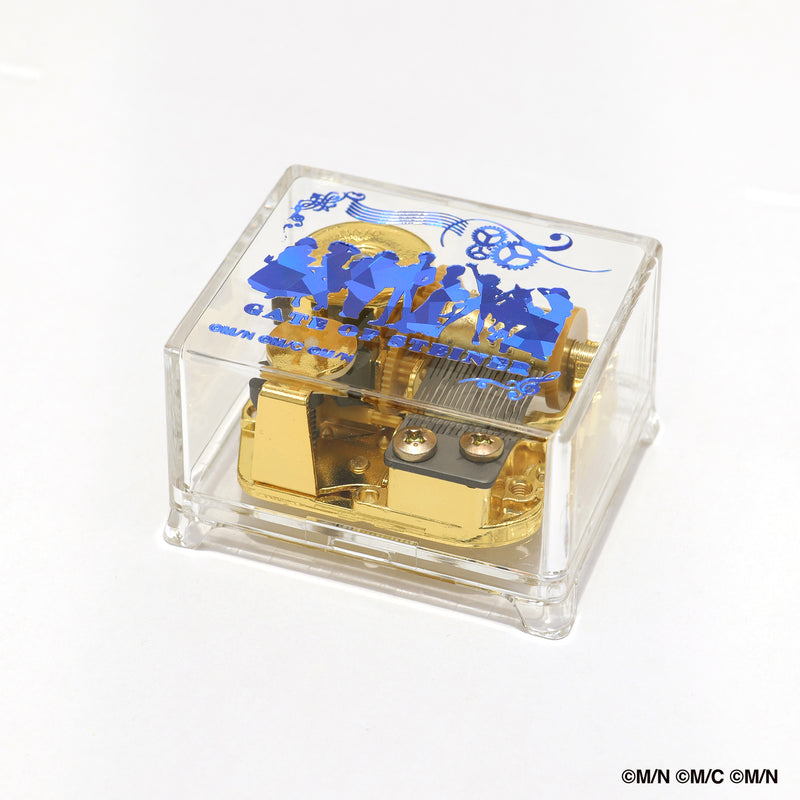 Clear acrylic-cased music box showing a gold-tone mechanism with blue Steins;Gate silhouettes printed on the top.