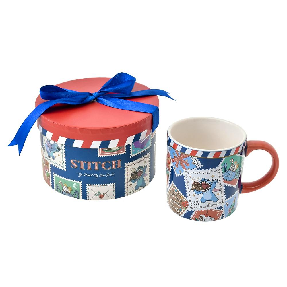 A Stitch & Scrump patterned mug displayed next to its round gift box with a red lid and blue ribbon.