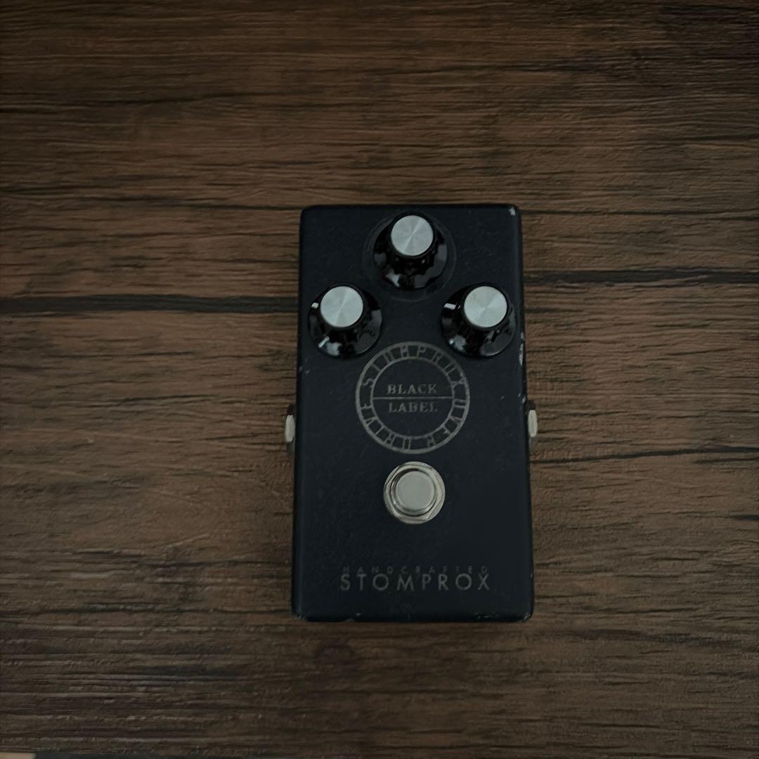 Top view of the STOMPROX BLACK LABEL guitar effects pedal showing three knobs, a footswitch, and the pedal label.
