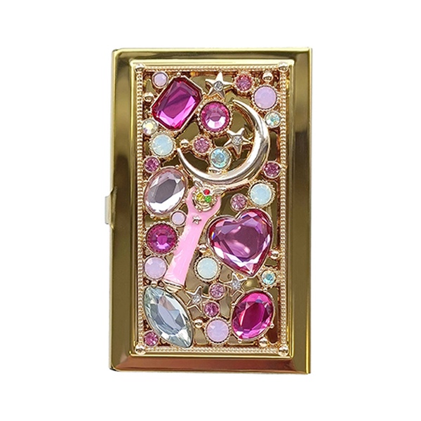 Front view of a metal stone-decorated business card case featuring a moon-stick motif.