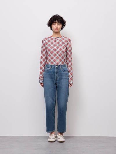 Front view of a model wearing the women's straight ankle jeans paired with a patterned long-sleeve top and sneakers.