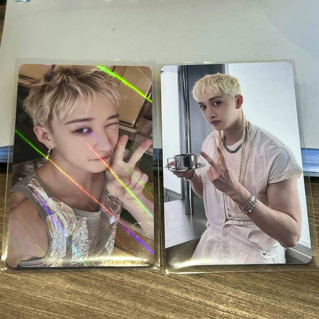 Two Stray Kids photocard fronts showing a blond-haired member posing and making a peace sign, one card with holographic diagonal lines.