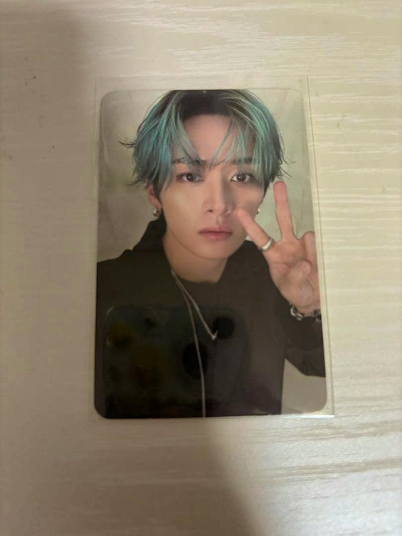 Photocard front showing a person with blue-green hair making a peace sign against a neutral background.