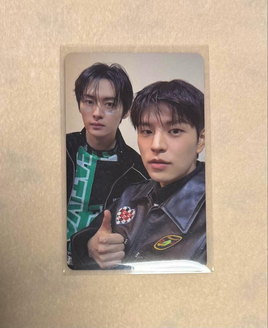 Front of the photocard showing two people posing inside a clear plastic sleeve on a beige background.