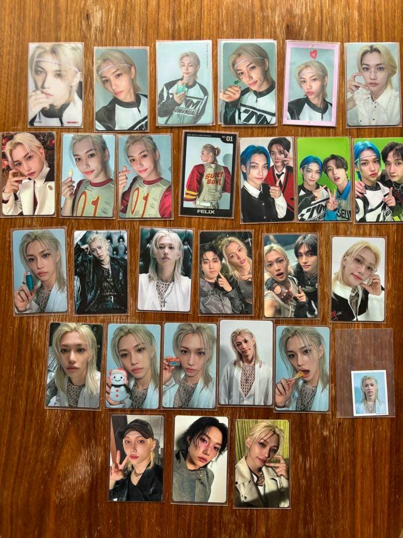 Many Stray Kids Felix photocard fronts arranged in rows on a wooden wood surface.