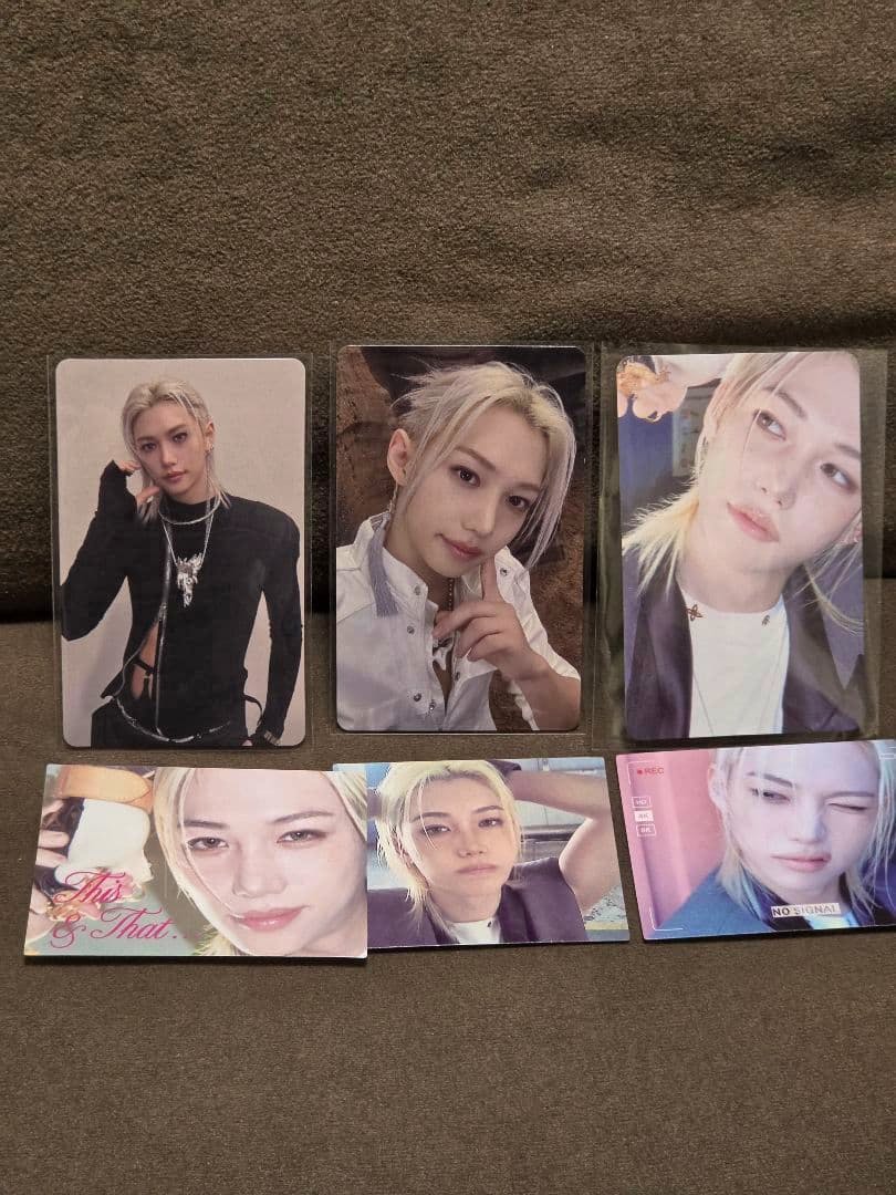 Six photocards from the THIS&THAT release arranged on a fabric surface.