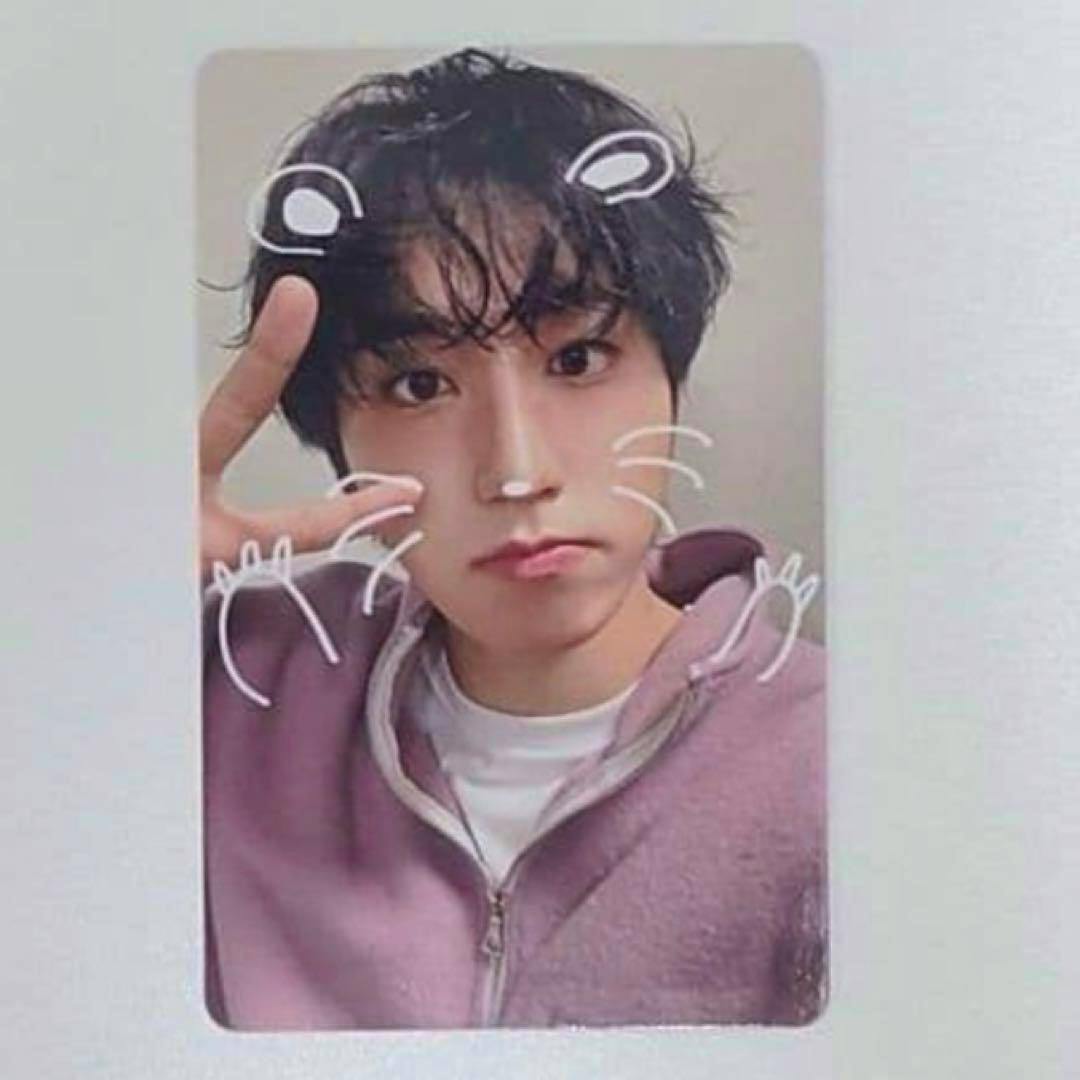 Front of the photocard showing a person in a purple zip-up jacket making a peace sign with white doodle whiskers and ears.