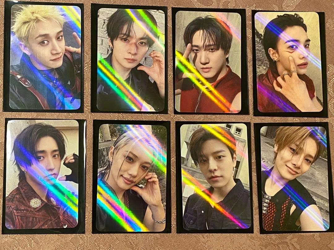 Eight Stray Kids holographic photocards arranged in two rows of four on a fabric surface.