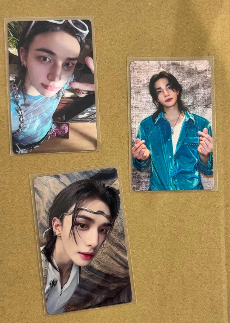 Three Stray Kids THIS & THAT photocards showing Hyunjin front photos placed on a brown surface.