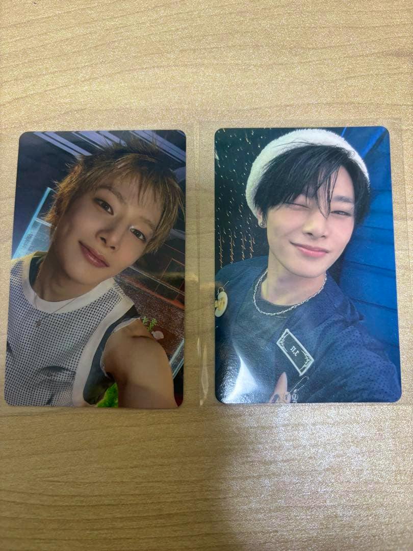 Two Stray Kids photocards with portrait photos of members placed side by side on a wooden surface.