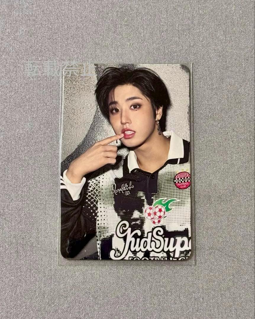 A Stray Kids KARMA photocard showing a close-up portrait of a member laid on gray fabric.