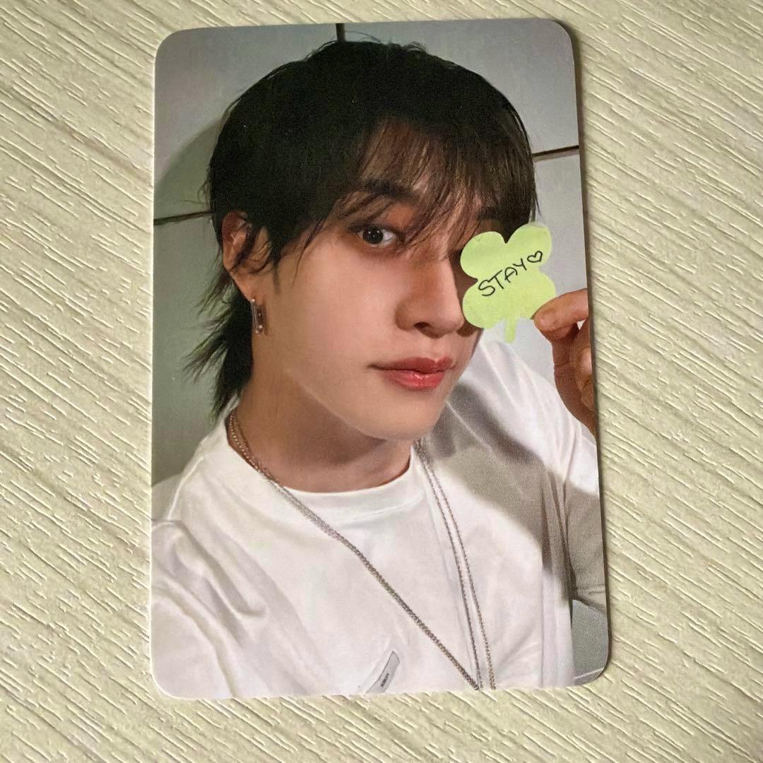 Front of the photocard showing a person in a white shirt holding a small green note that reads "STAY".