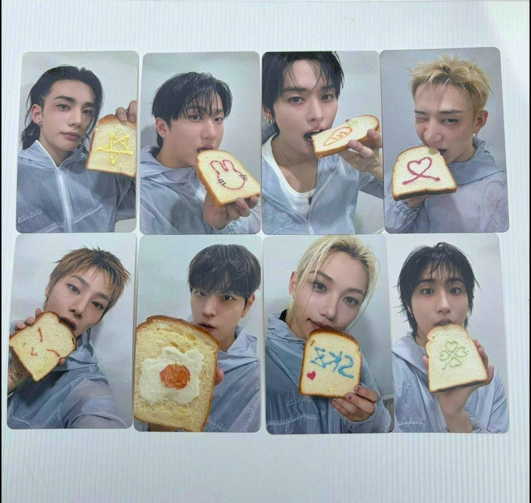 Photo of eight Stray Kids photocards arranged in two rows, each card showing a member holding a decorated slice of bread.