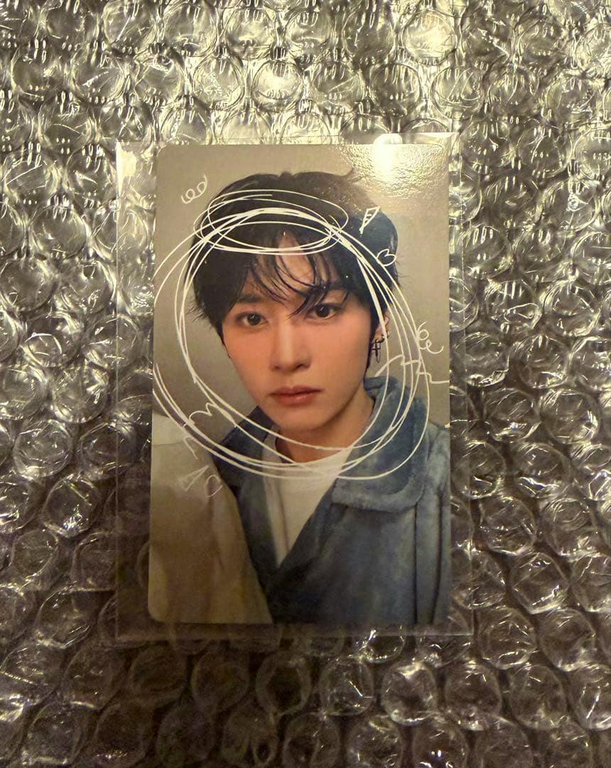 A Stray Kids photocard in a plastic sleeve placed on bubble wrap, showing a close-up portrait of a member.