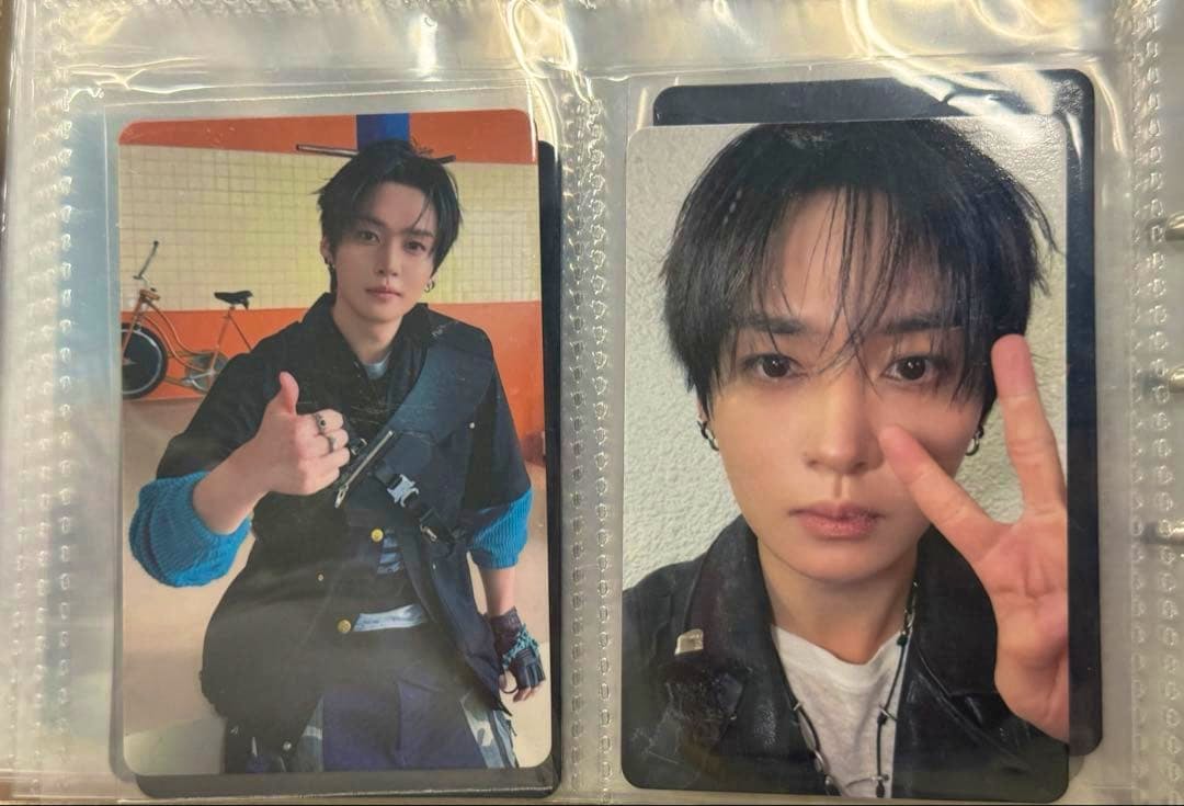 Two Stray Kids photocard trading cards displayed in a plastic sleeve, one showing a seated thumbs-up pose and the other a close-up peace-sign selfie.