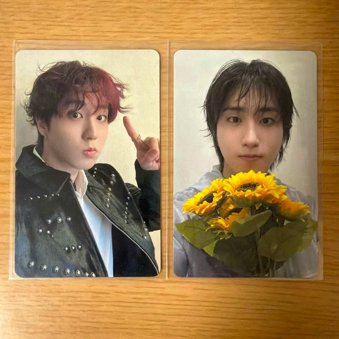 Two Stray Kids RUN IT photocard fronts showing portrait photos of a member in protective sleeves placed on a wooden surface.