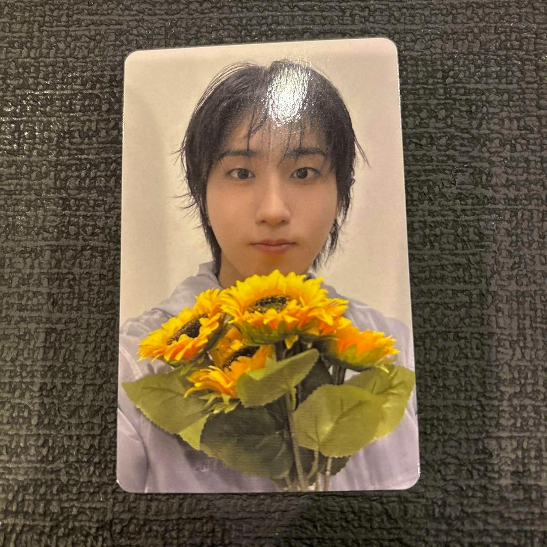 Photocard (Stray Kids RUN IT Nagoya venue-limited) showing a person holding a bouquet of sunflowers against a light background.