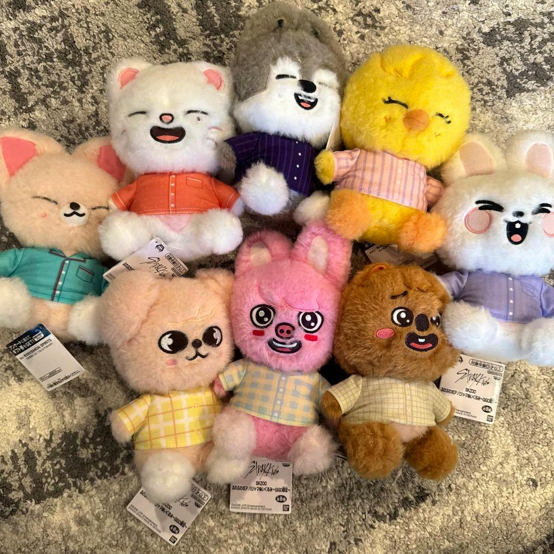 Eight StrayKids SKZOO fluffy pajama plush toys arranged on a carpet, showing various characters.