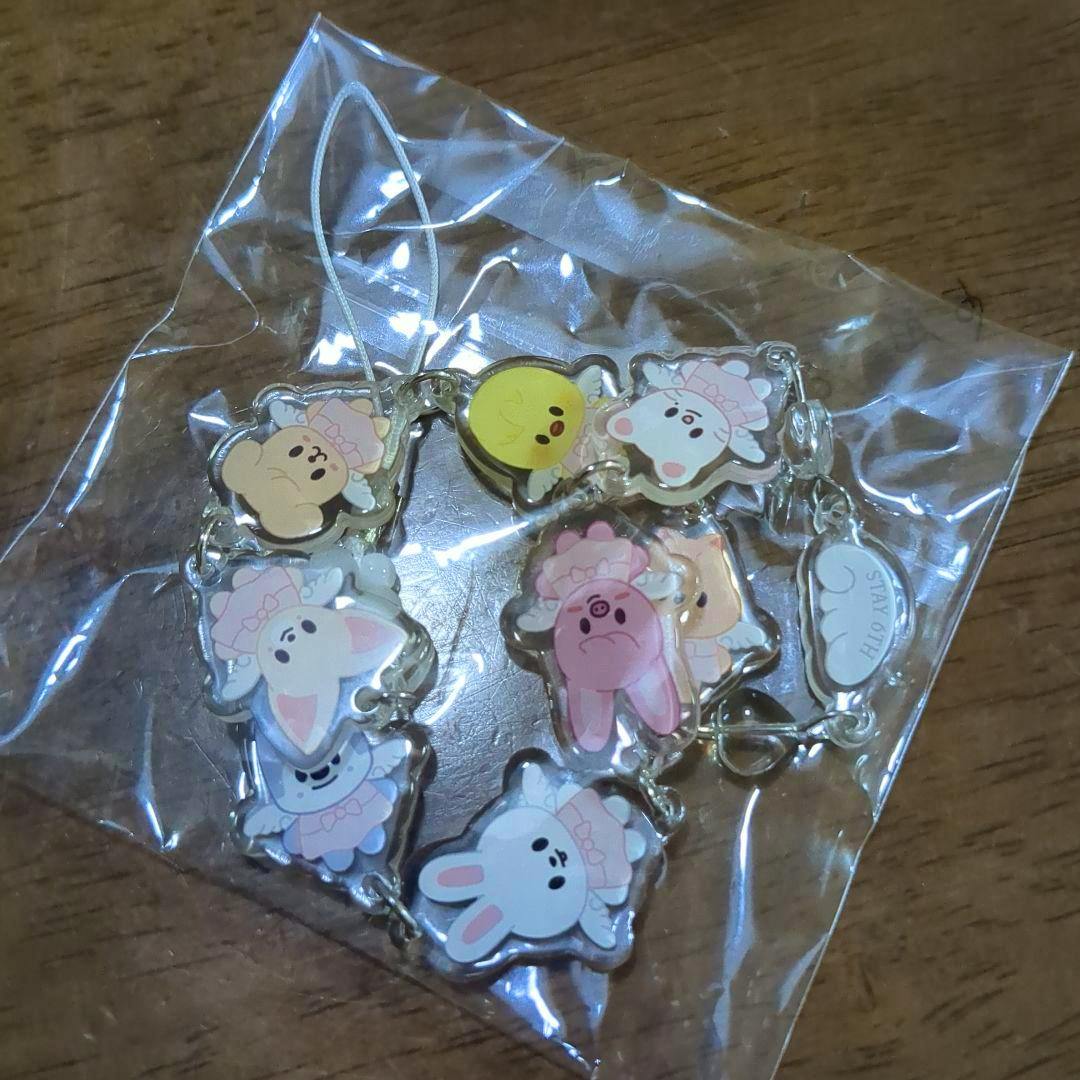 A Stray Kids STAY acrylic keychain (skzoo) showing multiple character charms inside a clear plastic bag on a wooden surface.
