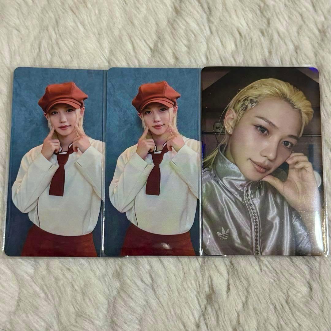 Three Stray Kids Felix photocards laid on a textured fabric background, two identical portrait cards and one reflective holographic-style portrait.