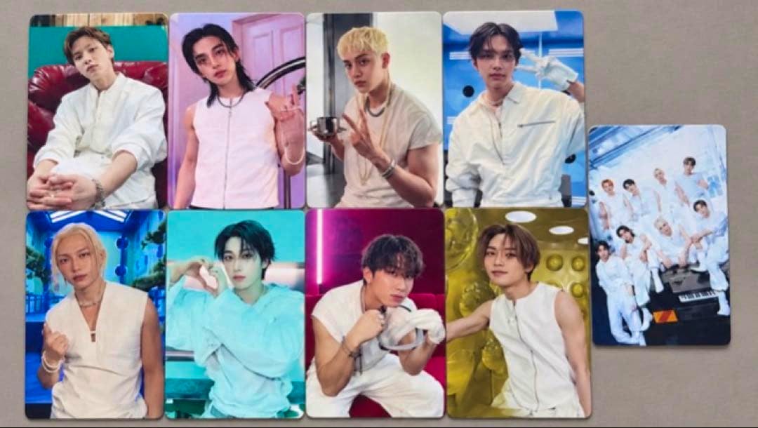 Nine Stray Kids photocards from THIS&THAT arranged on a gray surface, showing individual member photos and one group card.