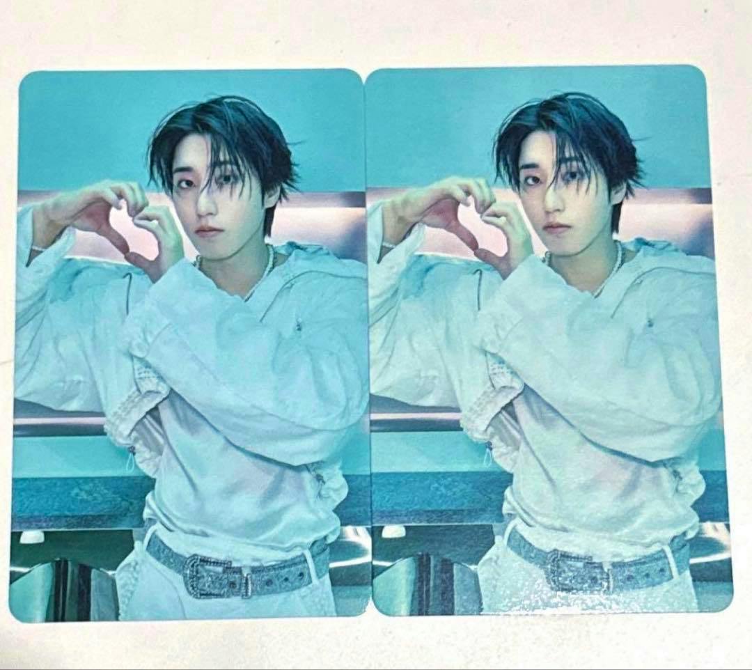 Two identical photocards showing a person in a light-colored jacket forming a heart with their hands, placed on a white background.